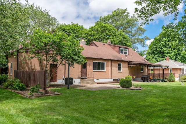 rear view of house featuring cooling unit, brick siding, fence, a yard, and a patio area