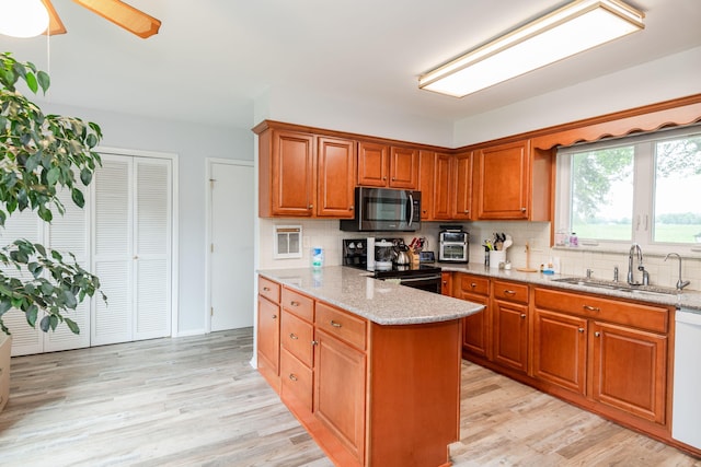 kitchen featuring black / electric stove, a sink, decorative backsplash, light wood finished floors, and stainless steel microwave