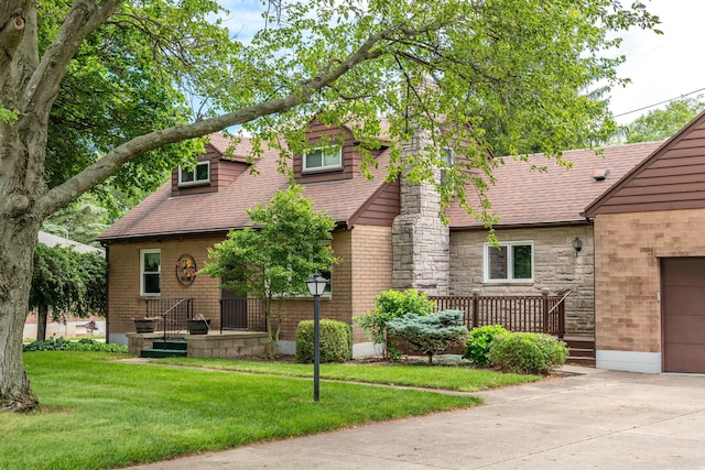 view of front of home featuring a garage, a shingled roof, stone siding, a front yard, and brick siding