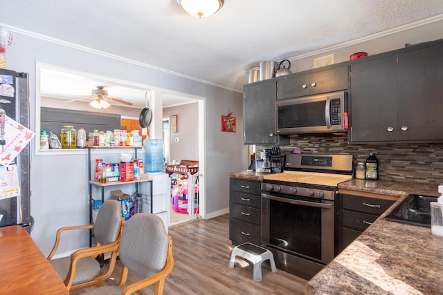 kitchen featuring stainless steel appliances, tasteful backsplash, light wood-style flooring, ornamental molding, and ceiling fan