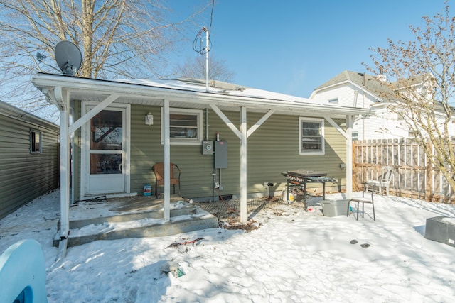 snow covered rear of property with fence