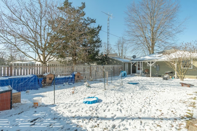 yard layered in snow with a pool and fence