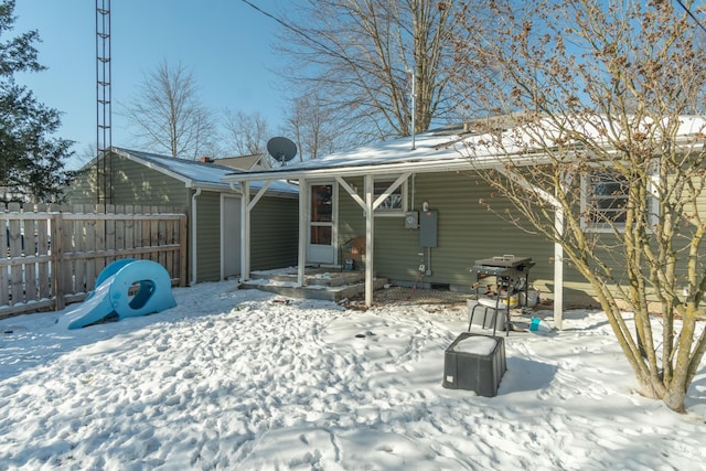 snow covered back of property featuring fence