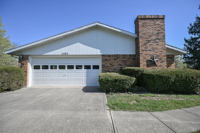 5283 Willow Dale Rd, Urbana, OH 43078 - view of home's exterior with brick siding, an attached garage, a chimney, and concrete driveway
