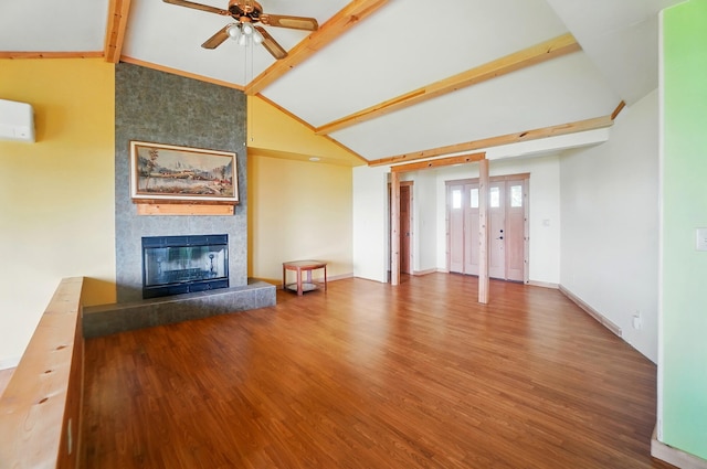 unfurnished living room with ceiling fan, lofted ceiling with beams, a tiled fireplace, a wall unit AC, and wood finished floors