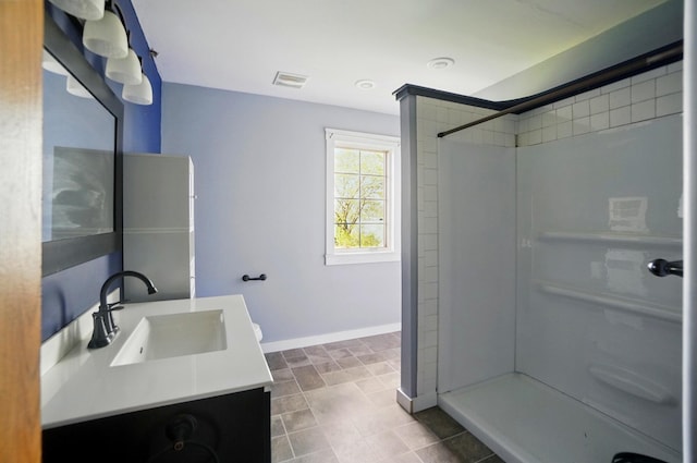bathroom with visible vents, baseboards, walk in shower, and vanity