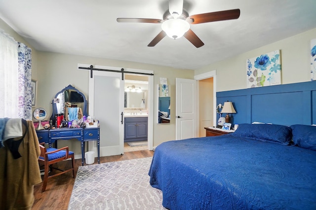 2206 State Route 56, London, OH 43140 - bedroom featuring a barn door, wood finished floors, a sink, a ceiling fan, and ensuite bathroom