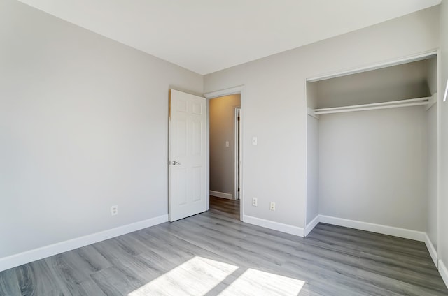 unfurnished bedroom featuring a closet, baseboards, and wood finished floors