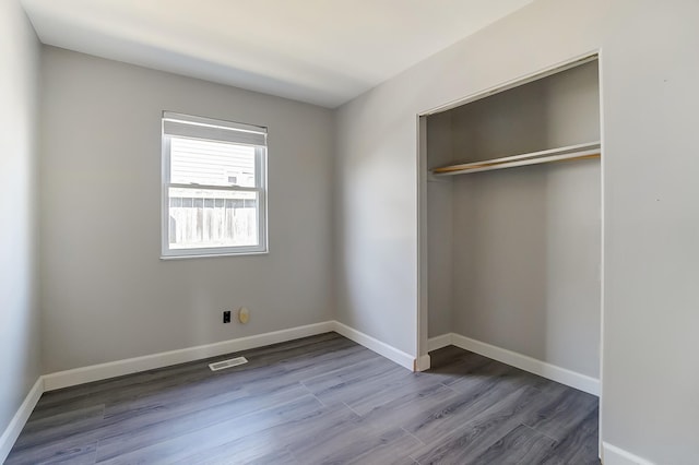 unfurnished bedroom with visible vents, baseboards, a closet, and wood finished floors