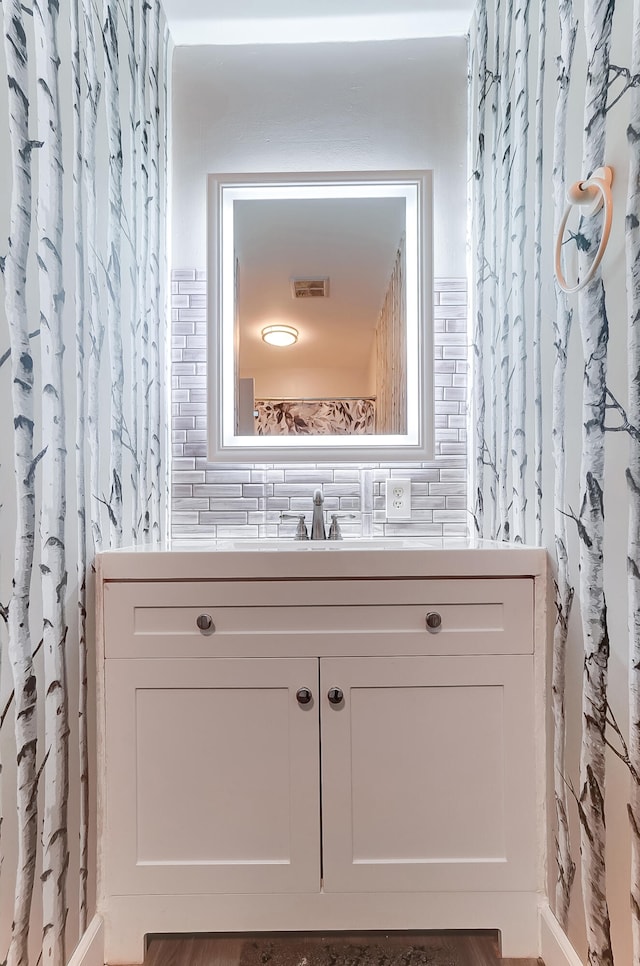 bathroom with visible vents, backsplash, and vanity