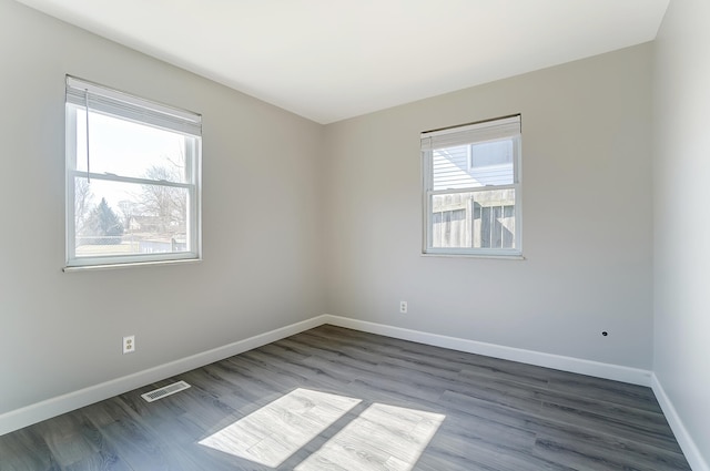 unfurnished room with visible vents, baseboards, and wood finished floors