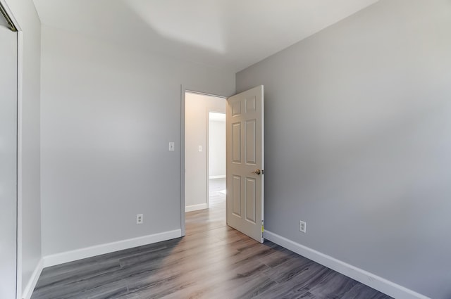 spare room with baseboards and wood finished floors