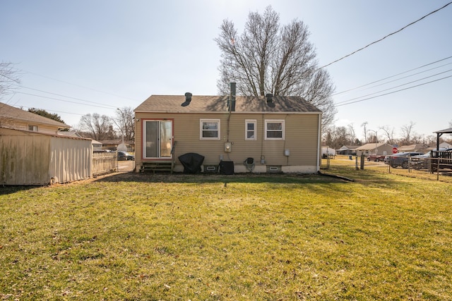 rear view of property with a lawn and fence