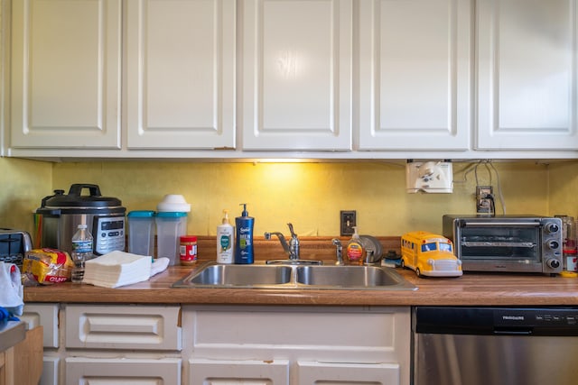 kitchen featuring a toaster, white cabinets, a sink, and stainless steel dishwasher