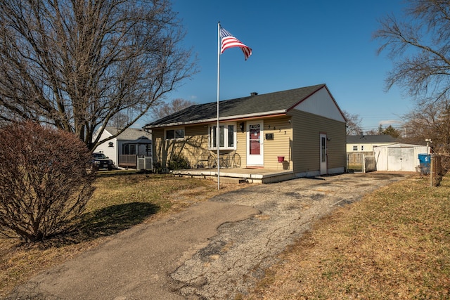 ranch-style home with an outbuilding, a front lawn, and a shed