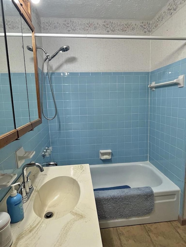 full bath with shower / bath combination, tile patterned flooring, tile walls, and a textured ceiling