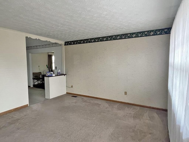 carpeted empty room featuring baseboards and a textured ceiling