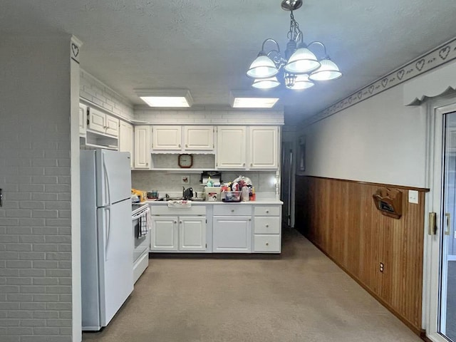 kitchen featuring white appliances, wooden walls, a wainscoted wall, light countertops, and white cabinetry