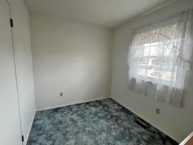 carpeted spare room with visible vents and baseboards