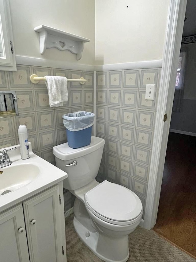 half bath with tile patterned flooring, a wainscoted wall, vanity, and toilet