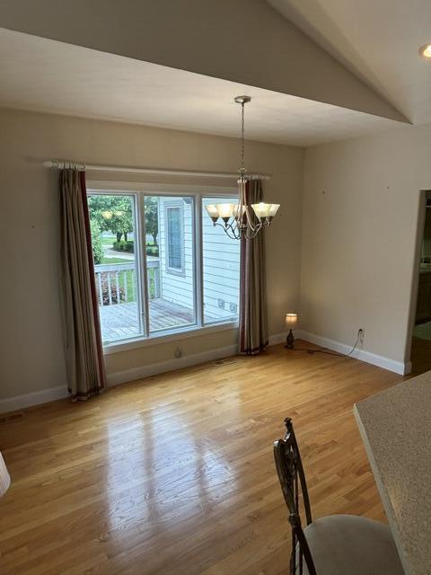 207 Meadowbrook Ln, Saint Marys, OH 45885 - unfurnished dining area with baseboards, a chandelier, wood finished floors, and lofted ceiling