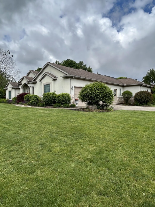 207 Meadowbrook Ln, Saint Marys, OH 45885 - view of property exterior featuring a yard, stucco siding, a garage, and driveway