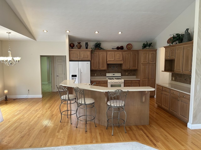 207 Meadowbrook Ln, Saint Marys, OH 45885 - kitchen with white appliances, vaulted ceiling, light wood-style floors, decorative backsplash, and a kitchen breakfast bar