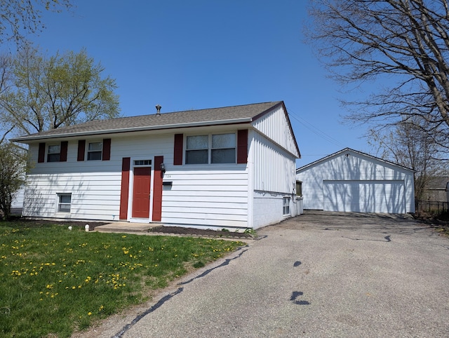 1124 Bookwalter Ave, New Carlisle, OH 45344 - bi-level home featuring an outbuilding, a detached garage, a front lawn, and a shingled roof