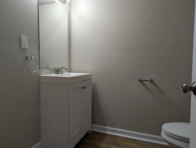 1124 Bookwalter Ave, New Carlisle, OH 45344 - half bathroom featuring toilet, vanity, wood finished floors, and baseboards