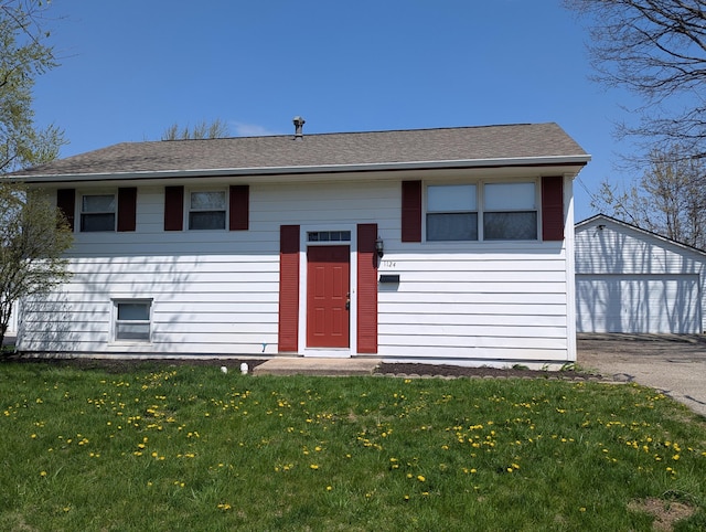 1124 Bookwalter Ave, New Carlisle, OH 45344 - raised ranch featuring a front lawn, a garage, a shingled roof, and an outdoor structure