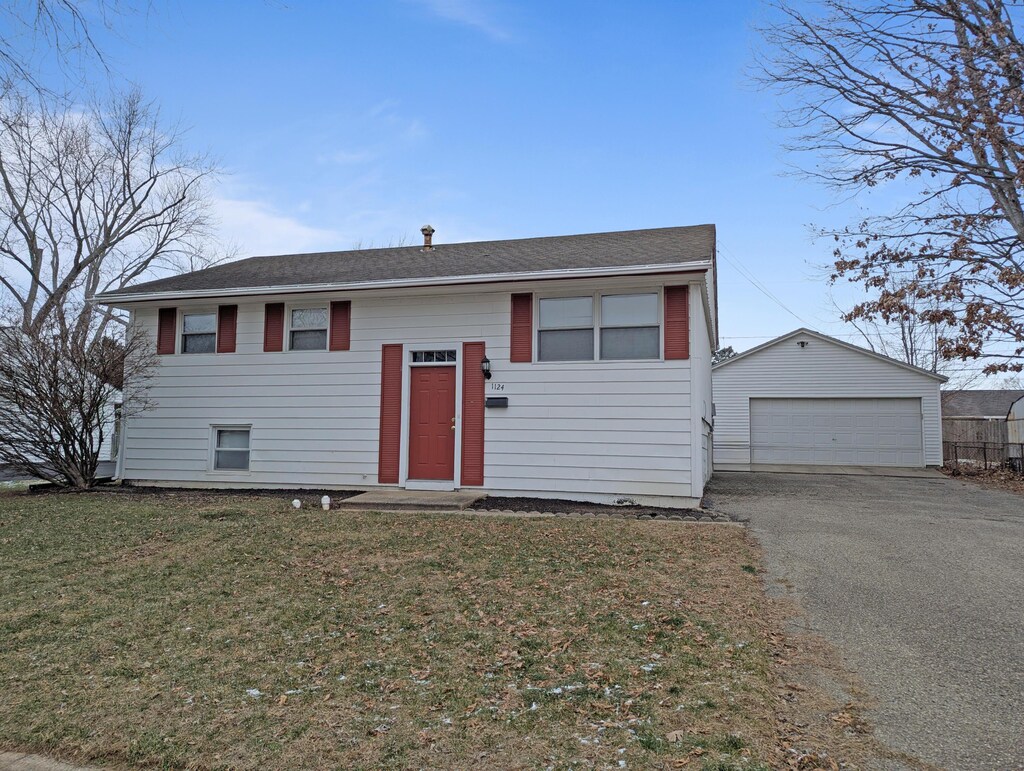 1124 Bookwalter Ave, New Carlisle, OH 45344 - raised ranch featuring a front lawn, a garage, a shingled roof, and an outdoor structure