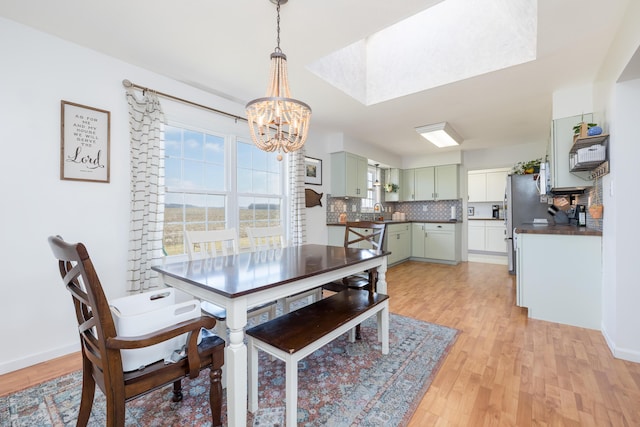 dining area featuring sink, a notable chandelier, and light hardwood / wood-style flooring