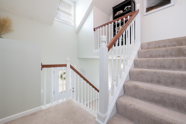 stairs with a towering ceiling, carpet, and a wealth of natural light