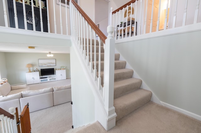 stairway featuring carpet flooring and a high ceiling