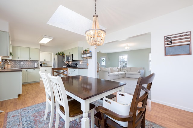 dining room with sink, light hardwood / wood-style floors, and a chandelier