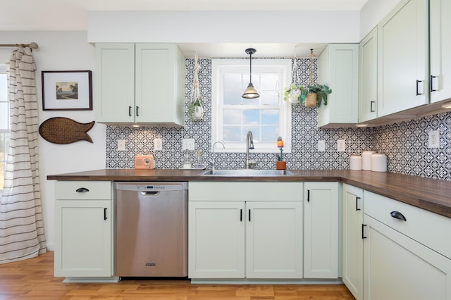 kitchen featuring wood counters, sink, hanging light fixtures, stainless steel dishwasher, and light wood-type flooring