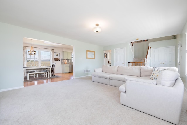 carpeted living room featuring an inviting chandelier