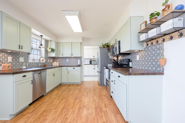 kitchen with sink, light hardwood / wood-style flooring, backsplash, stainless steel appliances, and wood counters