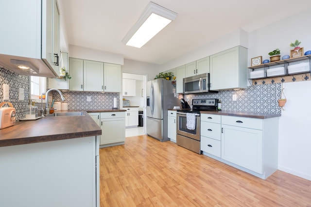 kitchen featuring butcher block countertops, decorative backsplash, stainless steel appliances, and sink