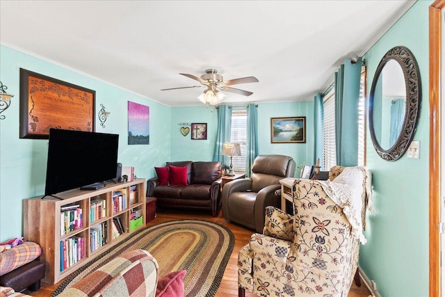 living area featuring crown molding, wood finished floors, and ceiling fan