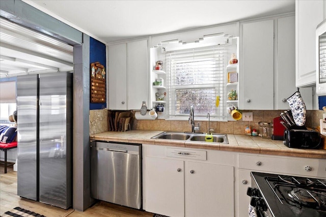 kitchen featuring a sink, white cabinets, tile countertops, and stainless steel appliances