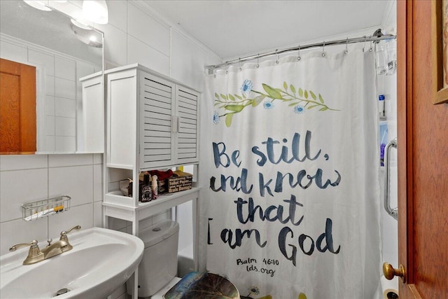 full bath featuring curtained shower, tile walls, ornamental molding, and a sink