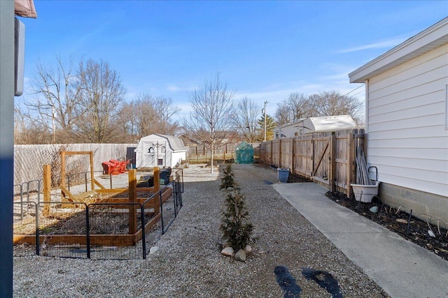 view of yard with a garden, an outdoor structure, a fenced backyard, and a shed