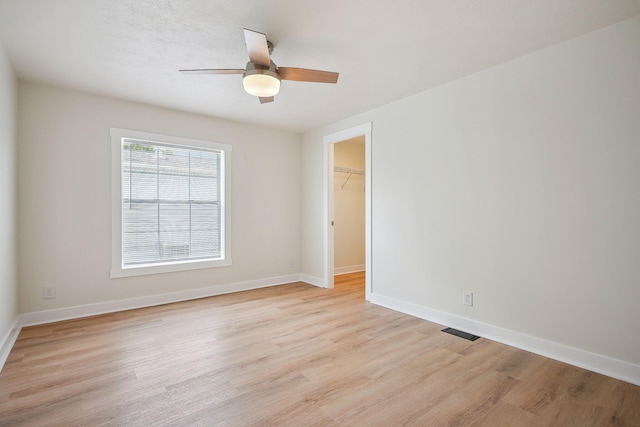 11579 Cooper Ave, Lakeview, OH 43331 - unfurnished bedroom featuring light wood-type flooring, a walk in closet, a closet, and a ceiling fan