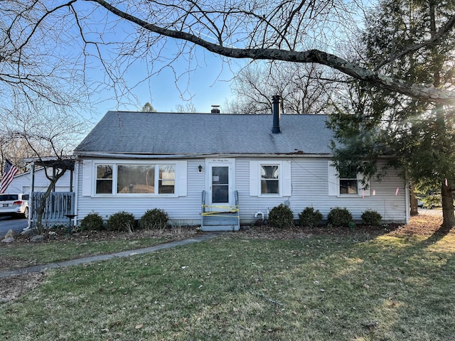 view of front facade featuring a shingled roof and a front lawn