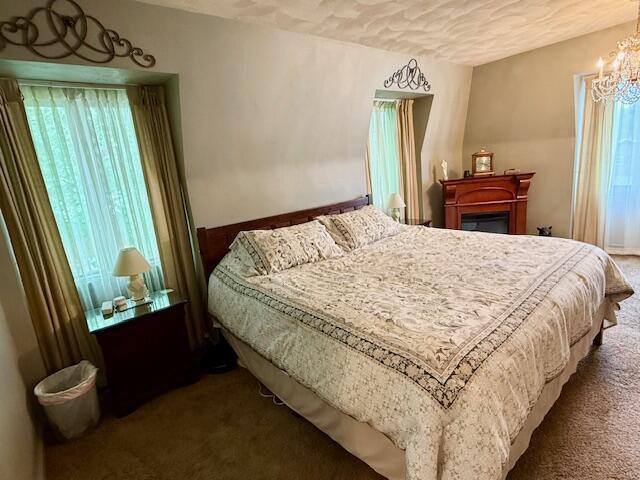 1337 Stratford Dr, Piqua, OH 45356 - bedroom with carpet flooring, a chandelier, and a fireplace