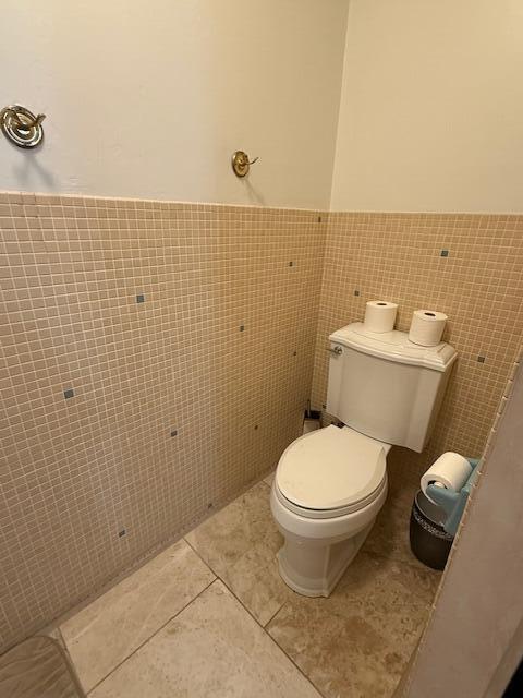1337 Stratford Dr, Piqua, OH 45356 - bathroom with tile walls, toilet, tile patterned floors, and a wainscoted wall