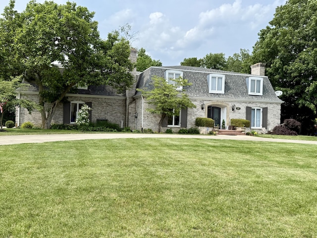 1337 Stratford Dr, Piqua, OH 45356 - view of front of property with a chimney, brick siding, a shingled roof, a front yard, and mansard roof