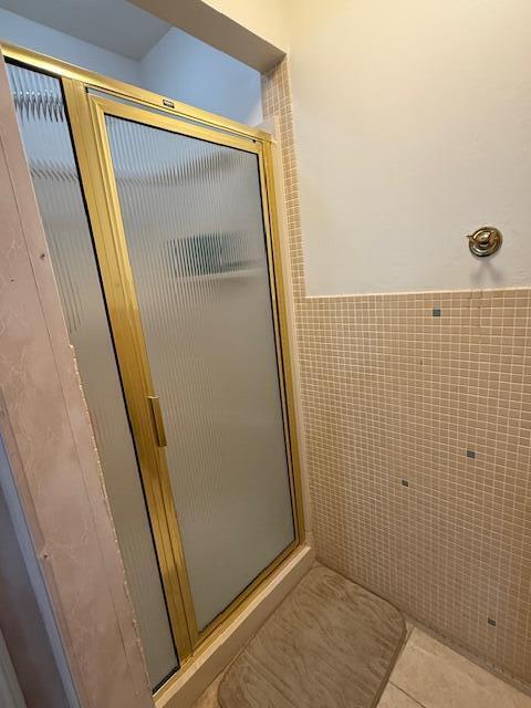 1337 Stratford Dr, Piqua, OH 45356 - bathroom with a stall shower, tile patterned flooring, tile walls, and a wainscoted wall