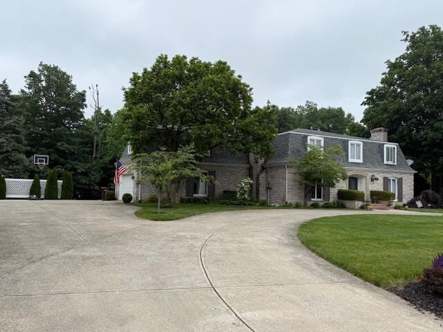 1337 Stratford Dr, Piqua, OH 45356 - view of front of house featuring curved driveway, a front lawn, a chimney, and a garage